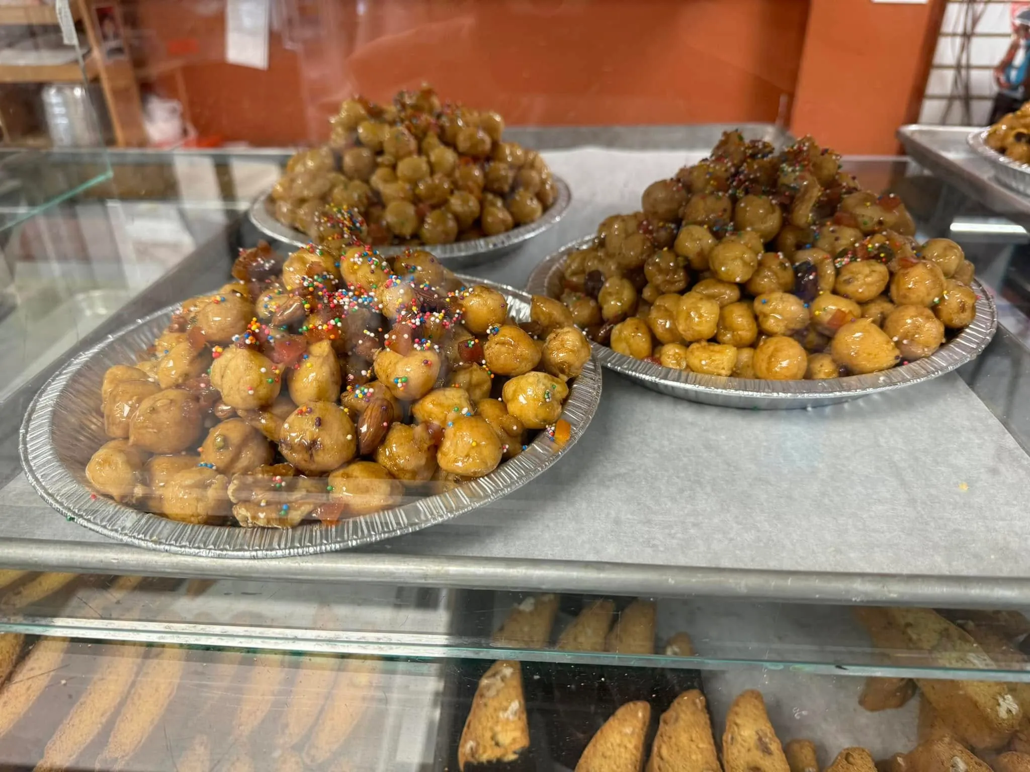 Trays of struffoli, small honey-glazed dough balls with sprinkles, on the bakery counter